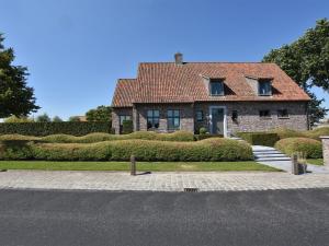 a large brick house with a red roof at Mansion with Jacuzzi and swim pond in Lichtervelde