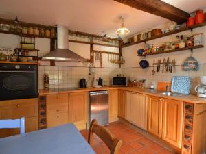 a large kitchen with wooden cabinets and a stove at Enchanting Cottage with Terrace Garden in Hamoir