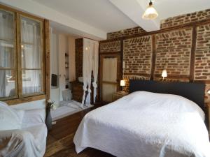 a bedroom with a white bed and a brick wall at Enchanting Cottage with Terrace Garden in Hamoir