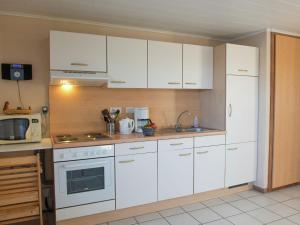 una cocina con armarios blancos y un horno de fogón blanco en Renovated Cottage in Corn mont with Garden en Louveigné