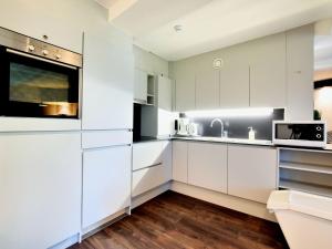 uma cozinha branca com armários e electrodomésticos brancos em Modern and comfortably furnished apartment em Robertville