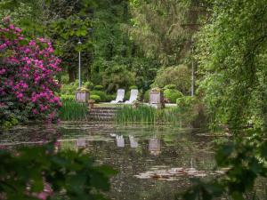 een tuin met een vijver met stoelen en bloemen bij Delightful Chalet in Opglabbeek near Lake in Opglabbeek