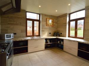 cocina grande con armarios de madera y microondas en A large family house, en Stavelot