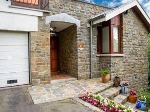 una casa de ladrillo con una puerta y flores delante de ella en A small studio of a nature stone house, en Aywaille