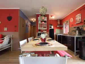 eine Küche mit roten Wänden und einem Holztisch und Stühlen in der Unterkunft Chalet in a green and peaceful environment in Houffalize