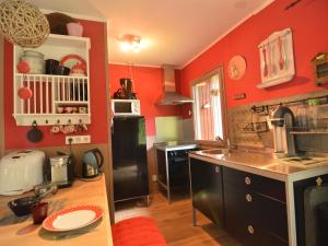 cocina con paredes rojas y nevera negra en Chalet in a green and peaceful environment, en Houffalize