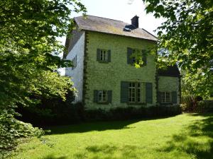 Quiet cottage in Roumont في Roumont: منزل حجري قديم في ساحة بها اشجار