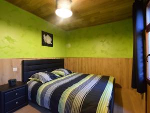 ナソーニュにあるVery welcoming and cosy chaletの緑の壁のベッドルーム1室、ベッド1台(枕2つ付)