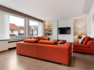 a living room with an orange couch and two chairs at Elegant Holiday Home in De Panne with Sauna in De Panne