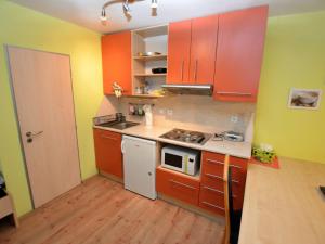 La cuisine est équipée de placards orange et d'une cuisinière blanche. dans l'établissement Comfy Holiday Home near Forest in Medenec, à Měděnec