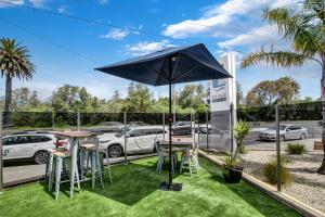 un patio con mesa, sillas y sombrilla en The Esplanade Resort And Spa en Lakes Entrance