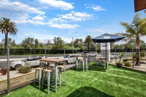 a patio with tables and an umbrella and grass at The Esplanade Resort And Spa in Lakes Entrance