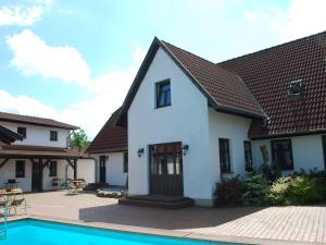 a white house with a pool in front of it at Schönes Ferienhaus in Dargun mit Pool in Barlin