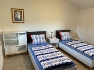 a bedroom with two beds and a cabinet at Schönes Ferienhaus in Dargun mit Pool in Barlin