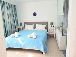 Un dormitorio con una cama azul con toallas. en White & Blue en Perivolos