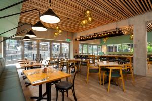 een restaurant met houten tafels, stoelen en ramen bij Nesuto Stadium in Auckland