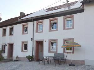 a white house with a table and chairs and an umbrella at Spacious Apartment in Meisburg with Terrace in Meisburg
