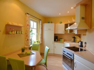 MadfeldにあるTasteful apartment near Brilon on the ground floor with terrace and gardenの黄色の壁のキッチン、テーブル(緑の椅子付)