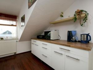 eine Küche mit weißen Schränken und einer Mikrowelle in der Unterkunft Apartment in Dietmannsried near the forest in Dietmannsried