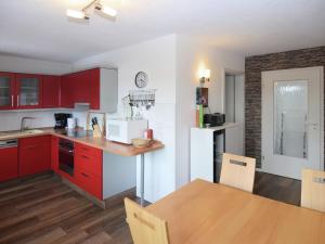 a kitchen with red cabinets and a table with a dining room at Beautiful holiday home in the Thuringian Forest with fireplace and whirlpool in Schnett