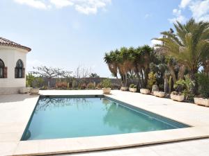 グラナディージャ・デ・アボナにあるBeautiful holiday home in San Isidro with poolのヤシの木が茂る家の裏庭にあるスイミングプール