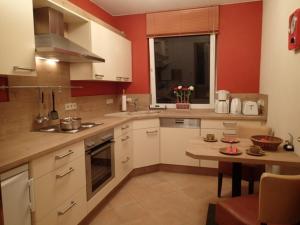 eine Küche mit roten Wänden, weißen Schränken und einem Tisch in der Unterkunft Schapers Ferienwohnungen in Emmerthal