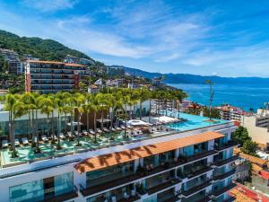 a building with palm trees and a body of water at PIER 57 - 710 Fabulous & Luxurious 2 BR Penthouse in Puerto Vallarta