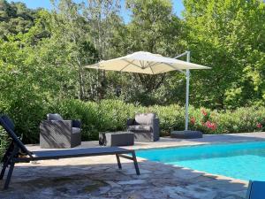 een parasol en stoelen naast een zwembad bij villa with private swimming pool in Roquebrun