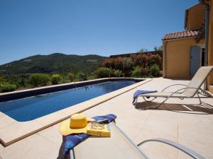 ein Pool mit Hut und Stühlen daneben in der Unterkunft Adorable Villa with in Roquebrun Swimming Pool in Roquebrun