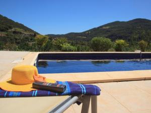 ein Strohhut auf einer Bank neben einem Pool in der Unterkunft Adorable Villa with in Roquebrun Swimming Pool in Roquebrun