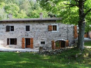 ein altes Steinhaus mit Holztüren und einem Baum in der Unterkunft Beautiful farmhouse in mountain forest setting in Saint-Bonnet-le-Froid