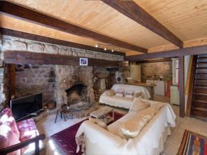 a living room with a stone fireplace and a couch at Beautiful farmhouse in mountain forest setting in Saint-Bonnet-le-Froid