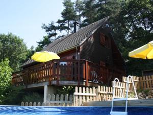 une maison en bois avec une terrasse et une piscine dans l'établissement Pretty chalet in Beaulieu with private pool, à Beaulieu