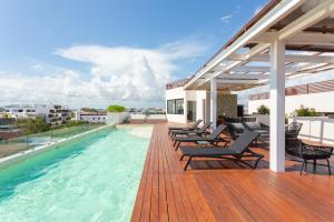 - une terrasse avec des chaises et une piscine dans un bâtiment dans l'établissement Studio Vanessa beach 42 a 1 min de la playa y 5ta av, à Playa del Carmen