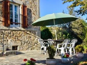 a table and chairs with a green umbrella at Comfortable holiday home with garden in Cassaniouze