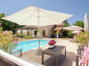 a table with an umbrella next to a swimming pool at Countryside villa in Polaca with private pool in Rouzède
