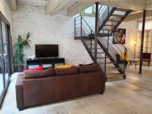 a living room with a brown couch and a staircase at Holiday home near the Canal du Midi in Olonzac
