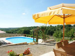 una piscina con ombrellone e tavolo e sedie di Charming holiday home with pool a Lavercantière