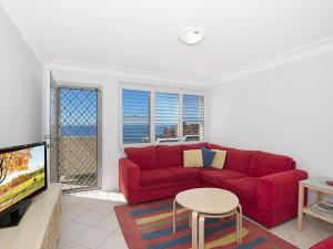 Una sala de estar con un sofá rojo y un televisor. en Werrina Townhouse, en The Entrance