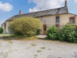 Una casa vieja con un árbol delante. en Cottage in an old remote farmhouse near Ch teauroux, en Giroux