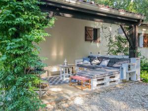 um pátio com um sofá e uma mesa em Quiet holiday home with large pool em Saint-Martin-le-Redon