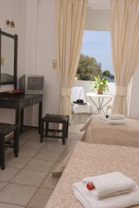 a bedroom with two beds and a desk and a piano at Akti Corali Hotel in Amoudara Herakliou