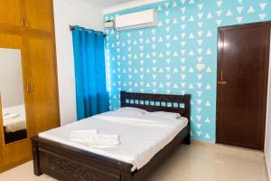 Un dormitorio con una cama con una pared azul y blanca en Fiji Villa, en Pondicherry