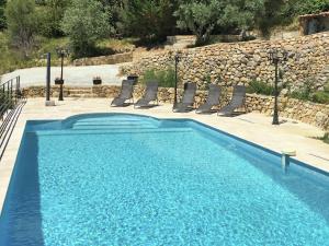 a blue swimming pool with chairs and a rock wall at Beautiful holiday home with private pool in Ampus