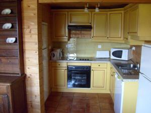 a kitchen with yellow cabinets and a stove top oven at Rustic chalet with dishwasher, in the High Vosges in Le Ménil