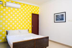 Cama en habitación con pared amarilla en Fiji Villa, en Pondicherry