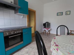 eine Küche mit blauen Schränken, einem Tisch, einem Tisch und einem Stuhl in der Unterkunft Charming Apartment in Vantacici amid the Sea in Dragozetići