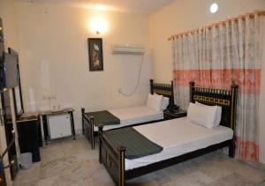 a room with two beds and a desk at Step inn Guest House Sukkur in Kalar Goth