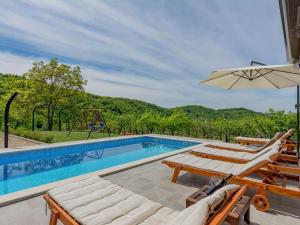 a swimming pool with two lounge chairs and an umbrella at Apartment in Istria with Nature Views in Cerovlje