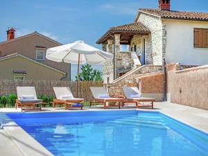 a swimming pool with two chairs and an umbrella at Modern Holiday Home in Porec with Swimming Pool in Nova Vas